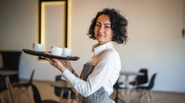 Kafe ya da lokantada çalışan olgun bir kadın garson kahve tepsisi taşıyor. İş yerindeki bayan girişimci. Gerçek insanlar uzay küçük işletme konseptini kopyalıyor.