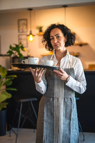 カフェやレストランで成熟した女性のカフェアジアのウェイトレスは 仕事でコーヒー女性起業家とトレイを運ぶ実際の人々はスペースをコピー小さなビジネスコンセプト — ストック写真