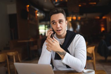 Kafe ya da restoranda masada oturan bir adam sıradan giyiniyor cep telefonuyla iletişim kuruyor ve elinde bir fincan kahve tutarken gerçek insanlar uzayı kopyalıyor.