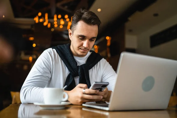 一位坐在餐馆或咖啡馆桌旁的男士 穿着休闲装 用手机上网或发短信 进行交流 — 图库照片