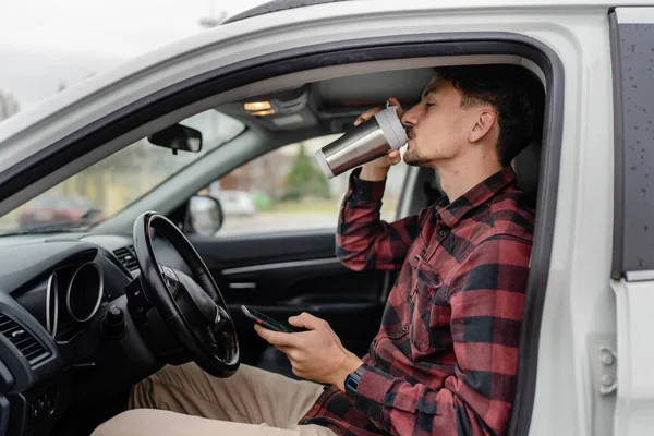 車の中で座って口ひげを生やしている1人の男白人男性は 道路上でブレーキを取ります旅行のホールドカップコーヒーは Smsテキストメッセージやナビゲーションアプリのための携帯電話のスマートフォンを使用して 実際の人々はスペースをコピー — ストック写真