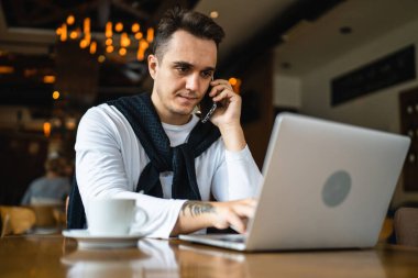 Kafe ya da restoranda masada oturan bir adam sıradan giyiniyor cep telefonuyla iletişim kuruyor ve elinde bir fincan kahve tutarken gerçek insanlar uzayı kopyalıyor.