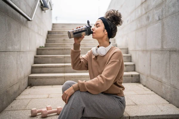 stock image One young woman with headphones prepare for training hold supplement shaker bottle to drink water stand outdoor beautiful sporty caucasian female generation z healthy lifestyle concept copy space