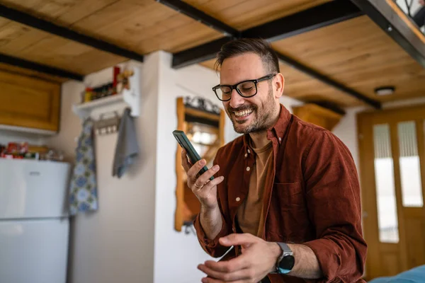 코카서스 남성은 침대에 셔츠를 안경을 사람의 사진을 스마트폰을 사용하여 미소를 — 스톡 사진