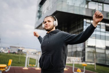 Şehirdeki açık spor salonunda antrenmandan önce ya da sonra esneyen bir adam. Gerçek insanlar sağlıklı yaşam tarzı konsepti. Amatör egzersiz.