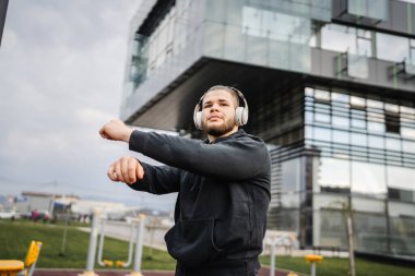 Şehirdeki açık spor salonunda antrenmandan önce ya da sonra esneyen bir adam. Gerçek insanlar sağlıklı yaşam tarzı konsepti. Amatör egzersiz.