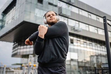 Şehirdeki açık spor salonunda antrenmandan önce ya da sonra esneyen bir adam. Gerçek insanlar sağlıklı yaşam tarzı konsepti. Amatör egzersiz.