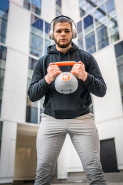 Kafkasyalı genç bir erkek sporcu gün içinde dışarıda Rus çanı Girya Kettlebell ağırlık egzersizi ile antrenman yapıyor.