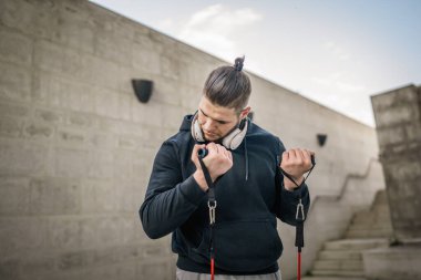 Yetişkin beyaz bir adam, günlük egzersiz rutininde lastik elastik direnç tüpleri kullanarak şehir dışında antrenman yapıyor. Gerçek insan sağlığı ve fitness konsepti kopyalama alanı kullanıyor.