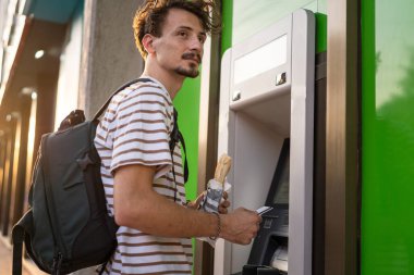 Bir adam genç yetişkin modern milenyum turisti ATM makinesiyle para çekmek için şehir yaşamını modern yaşam konseptini kullanıyor.