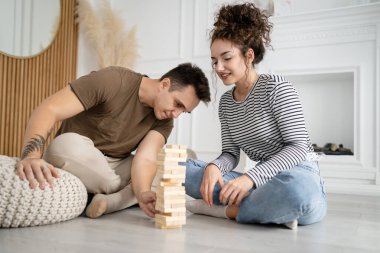 Kadın ve erkek mutlu beyaz çift ya da evde Jenga masası oyunu oynayan arkadaşlar mutlu bir gülücük keyfi birlikte vakit geçiriyorlar aile zamanlarını kopyalayan gerçek insanlar.