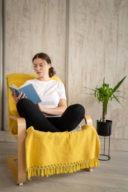 Genç bir kadın, beyaz kadın, evinde oturmuş kitap okuyor. Mekan fotokopisi çekiliyor. Gerçek insanlar hafta sonları boş vakit geçiriyorlar.