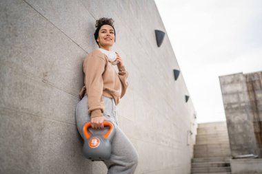 Kafkasyalı genç bir bayan sporcu gün içinde dışarıda Rus çanı Girya Kettlebell ağırlık egzersizi ile antrenman yapıyor.