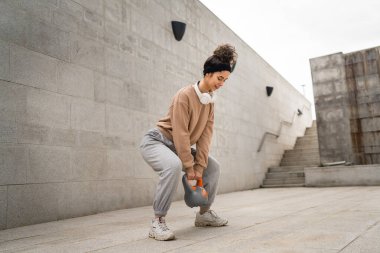 Kafkasyalı genç bir bayan sporcu gün içinde dışarıda Rus çanı Girya Kettlebell ağırlık egzersizi ile antrenman yapıyor.