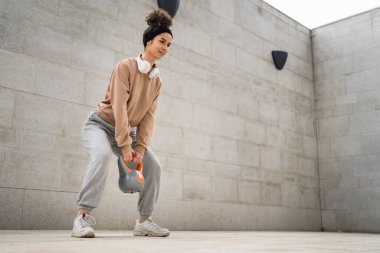 Kafkasyalı genç bir bayan sporcu gün içinde dışarıda Rus çanı Girya Kettlebell ağırlık egzersizi ile antrenman yapıyor.