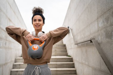 Kafkasyalı genç bir bayan sporcu gün içinde dışarıda Rus çanı Girya Kettlebell ağırlık egzersizi ile antrenman yapıyor.