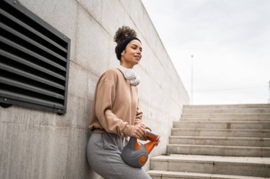 Kafkasyalı genç bir bayan sporcu gün içinde dışarıda Rus çanı Girya Kettlebell ağırlık egzersizi ile antrenman yapıyor.