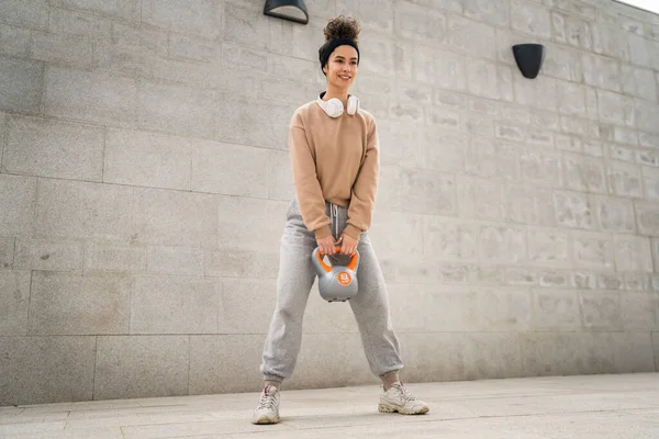 stock image One woman young caucasian female athlete stand outdoor in day training with russian bell girya kettlebell weight exercise real person copy space