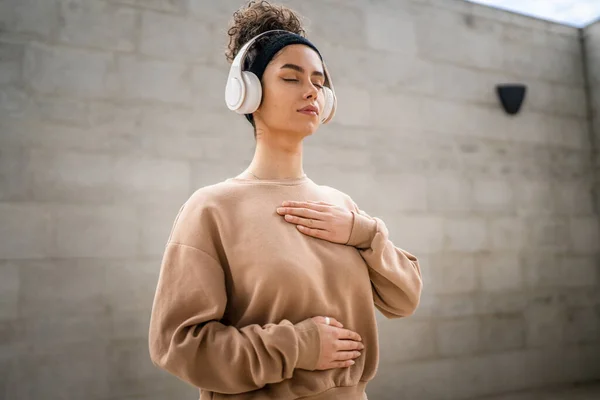 オンラインガイド付き瞑想のためのヘッドフォンを使用して1人の女性大人の白人女性目を閉じてマインドフルネス症状を練習屋外の現実の人々セルフケアコンセプトコピースペース — ストック写真