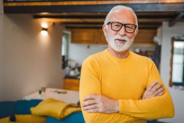 Gündüzleri evinde sakallı bir erkek büyükbabanın modern beyaz portresi sarı süveter giyiyor. Kendine güvenen bir fotokopi.
