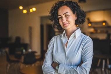 Yetişkin bir kadın Kafkas kadın iş kadını iş yerinde ya da evde duruyor gerçek insanlar yer kopyalıyor beyaz gömlek kıvırcık saçlar giyiyor