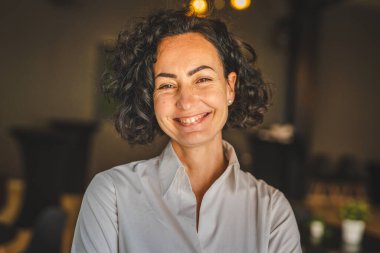 Yetişkin bir kadın Kafkas kadın iş kadını iş yerinde ya da evde duruyor gerçek insanlar yer kopyalıyor beyaz gömlek kıvırcık saçlar giyiyor