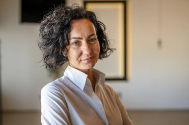 Yetişkin bir kadın Kafkas kadın iş kadını iş yerinde ya da evde duruyor gerçek insanlar yer kopyalıyor beyaz gömlek kıvırcık saçlar giyiyor