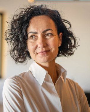 Yetişkin bir kadın Kafkas kadın iş kadını iş yerinde ya da evde duruyor gerçek insanlar yer kopyalıyor beyaz gömlek kıvırcık saçlar giyiyor