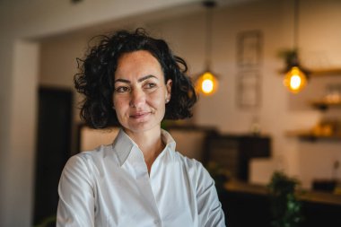 Yetişkin bir kadın Kafkas kadın iş kadını iş yerinde ya da evde duruyor gerçek insanlar yer kopyalıyor beyaz gömlek kıvırcık saçlar giyiyor