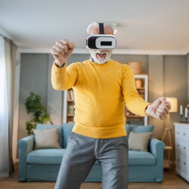 Yetişkin, yaşlı, beyaz bir erkek evde sanal gerçekliğin tadını çıkarıyor.