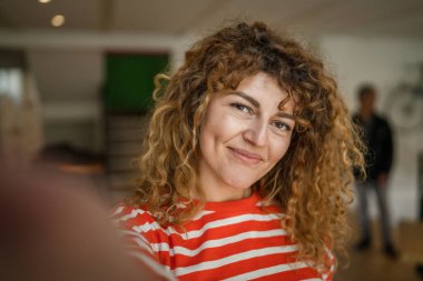 Kafkasyalı mutlu bir kadın kafenin içinde kıvırcık saçlı bir gülümsemeyle duruyor. Gerçek bir insan uzay portresi kopyası UGC Kullanıcı İçeriği