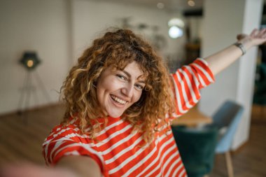 Kafkasyalı mutlu bir kadın kafenin içinde kıvırcık saçlı bir gülümsemeyle duruyor. Gerçek bir insan uzay portresi kopyası UGC Kullanıcı İçeriği