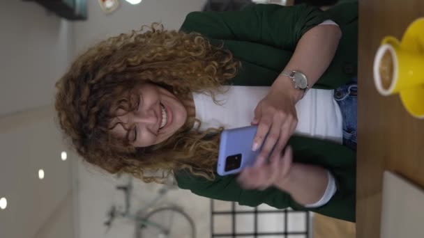 1人の女性大人Cucasian女性とともに巻き毛使用スマートフォン用オンラインテキストメッセージお祝い幸せな笑顔良いニュース自信を持って受信メッセージ愛と喜び本物の人々 — ストック動画
