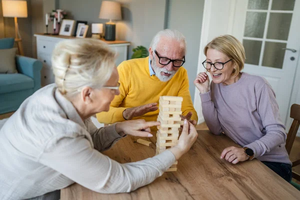 老一辈男人和女人夫妻朋友或家人在家里玩休闲棋盘游戏有乐趣的退休老人祖父和祖母和他们成熟的女儿在一起 — 图库照片