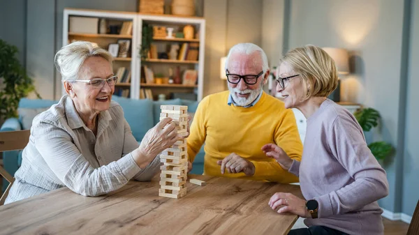 老一辈男人和女人夫妻朋友或家人在家里玩休闲棋盘游戏有乐趣的退休老人祖父和祖母和他们成熟的女儿在一起 — 图库照片
