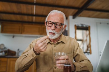 Kafkasyalı bir erkek büyükbaba evde oturur uyuşturucu tableti alır ağrı kesici içer ya da vitamin takviyesi alır. Etikette tıbbın gerçek insan sağlığı ve tıp kavramını okur.