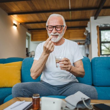 Kafkasyalı bir erkek büyükbaba evde oturur uyuşturucu tableti alır ağrı kesici içer ya da vitamin takviyesi alır. Etikette tıbbın gerçek insan sağlığı ve tıp kavramını okur.