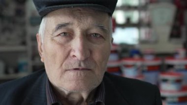 Kafkasyalı yaşlı bir adamın portresi. Büyükbaba içeride oturuyor. Şapka takıyor ve kameraya bakıyor.