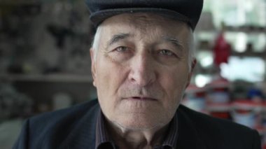 Kafkasyalı yaşlı bir adamın portresi. Büyükbaba içeride oturuyor. Şapka takıyor ve kameraya bakıyor.