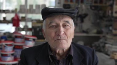 Kafkasyalı yaşlı bir adamın portresi. Büyükbaba içeride oturuyor. Şapka takıyor ve kameraya bakıyor.