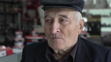 Kafkasyalı yaşlı bir adamın portresi. Büyükbaba içeride oturuyor. Şapka takıyor ve kameraya bakıyor.