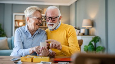 Üst düzey karı koca aile fotoğraflarına bakıyor. Kafkasyalı yaşlı erkek ve kadın büyükbaba ve büyükanne mutlu bir gülümseme. Evde eski resimlerle gerçek insanlar uzay kopyaları yapıyor.