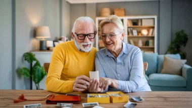 Üst düzey karı koca aile fotoğraflarına bakıyor. Kafkasyalı yaşlı erkek ve kadın büyükbaba ve büyükanne mutlu bir gülümseme. Evde eski resimlerle gerçek insanlar uzay kopyaları yapıyor.