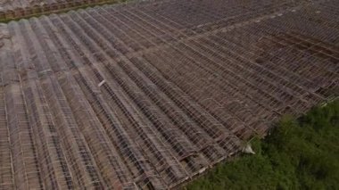 Paslı seraya insansız hava aracı görüntüsü tarladaki tarımsal alanda kırık parçalar ve cam parlaklığı ile dolu. 