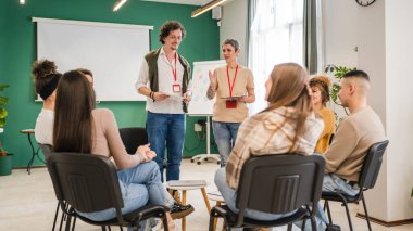Bir grup insan terapist erkek ve bir kadınla aynı çemberde oturuyor. Duygusal destek veriyorlar, sorunları çözüyorlar, zihinsel farkındalık ve benlik bakımı kavramını tartışıyorlar.