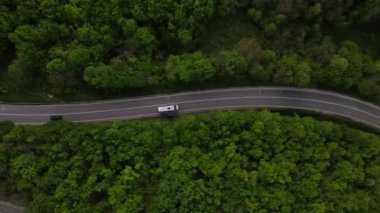 Sırbistan 'da yeşil ve manzara taşımacılığı ve seyahat konseptiyle çevrili dolambaçlı yol boyunca giden bahar aracı otomobili sırasında, bir dağ sırasındaki eğimli asfalt bir yolun hava aracı görüntüleri