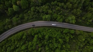 Sırbistan 'da yeşil ve manzara taşımacılığı ve seyahat konseptiyle çevrili dolambaçlı yol boyunca giden bahar aracı otomobili sırasında, bir dağ sırasındaki eğimli asfalt bir yolun hava aracı görüntüleri