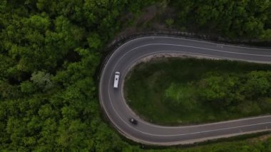 Sırbistan 'da yeşil ve manzara taşımacılığı ve seyahat konseptiyle çevrili dolambaçlı yol boyunca giden bahar aracı otomobili sırasında, bir dağ sırasındaki eğimli asfalt bir yolun hava aracı görüntüleri