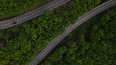 Sırbistan 'da yeşil ve manzara taşımacılığı ve seyahat konseptiyle çevrili dolambaçlı yol boyunca giden bahar aracı otomobili sırasında, bir dağ sırasındaki eğimli asfalt bir yolun hava aracı görüntüleri