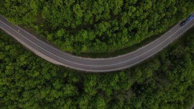 Sırbistan 'da yeşil ve manzara taşımacılığı ve seyahat konseptiyle çevrili dolambaçlı yol boyunca giden bahar aracı otomobili sırasında, bir dağ sırasındaki eğimli asfalt bir yolun hava aracı görüntüleri